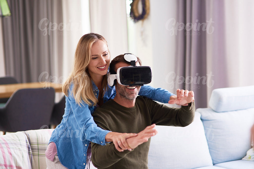 Modern couple using virtual reality simulator in living room