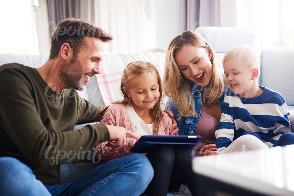 Happy family with tablet spending time together in living room