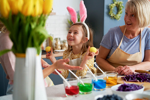 Little girl have fun during coloring Easter eggs with family