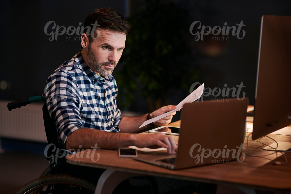 Side view of disabled man with documents working late