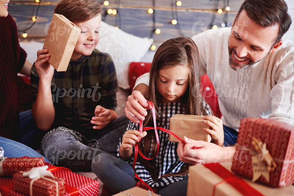 Happy children opening christmas present with parents