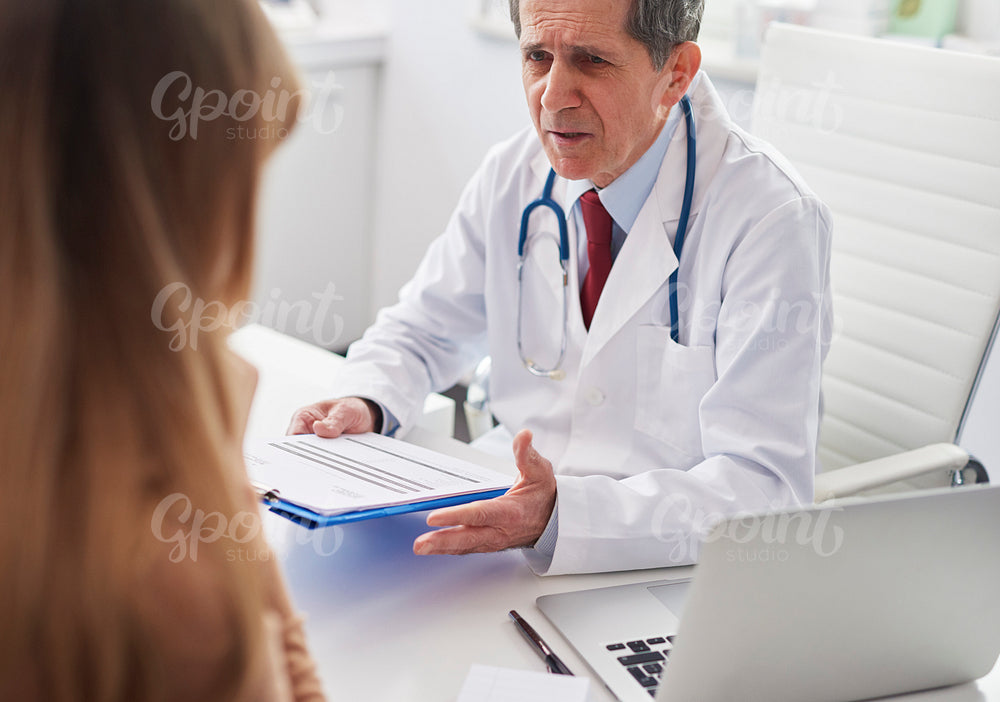 Senior doctor talking to woman in doctor’s office