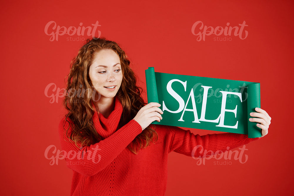 Young woman showing banner of sale at studio shot