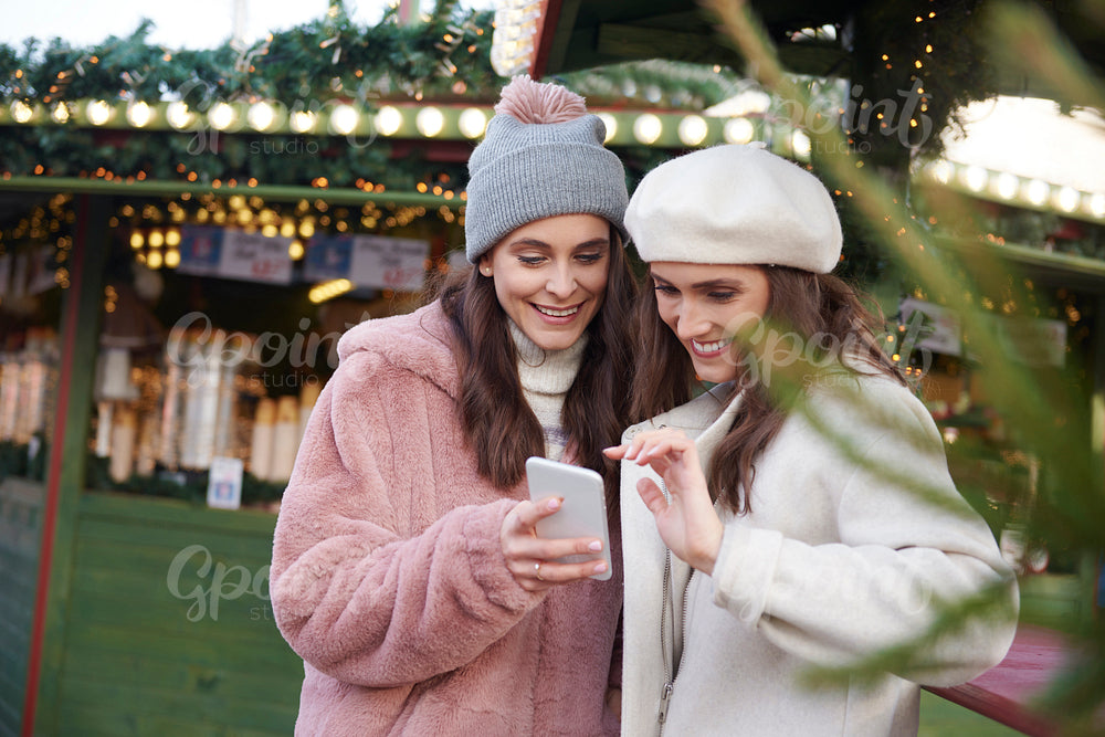 Women on the Christmas market browsing mobile phone