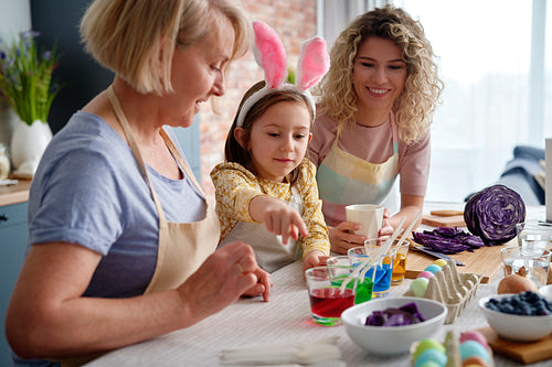 Little girl showing natural egg dyes with her family