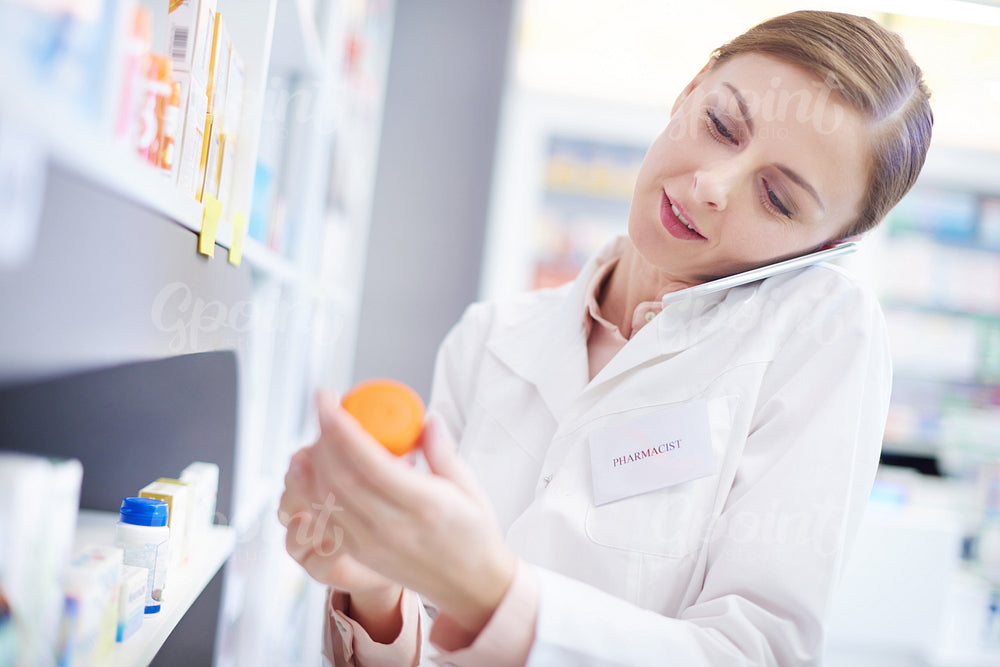 Female pharmacist on phone call reaching medication