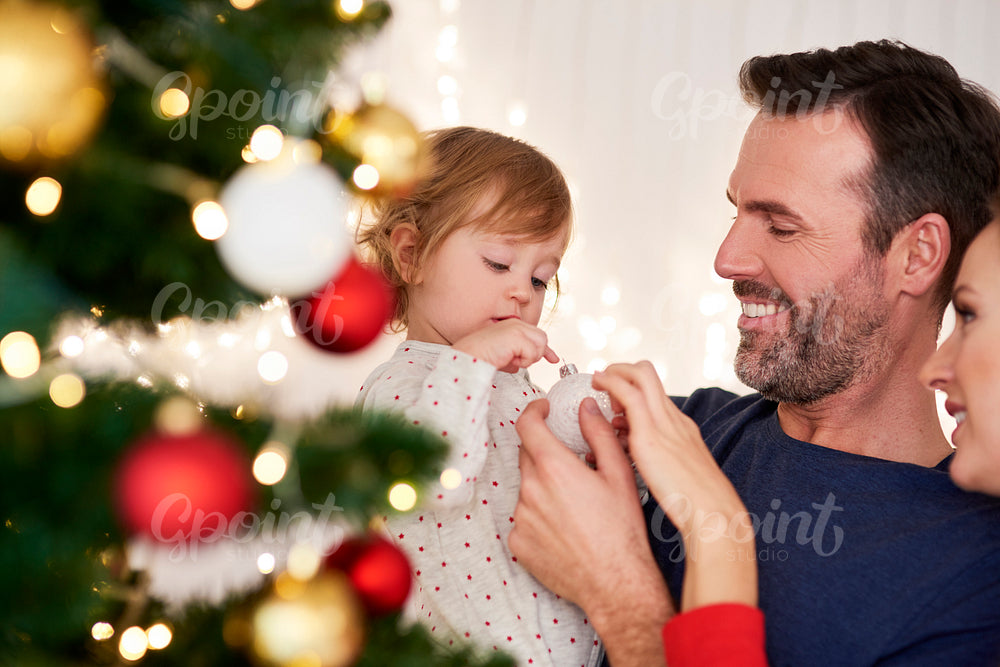 Parents with baby decorating Christmas tree