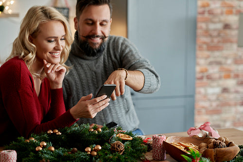 Couple with a Christmas wreath watching something on a phone