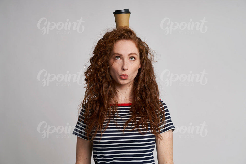 Funny girl with cup of coffee on the head