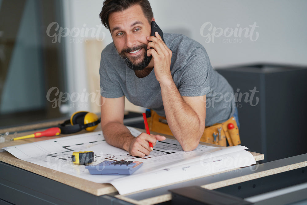 Smiling carpenter talking to a client on the phone