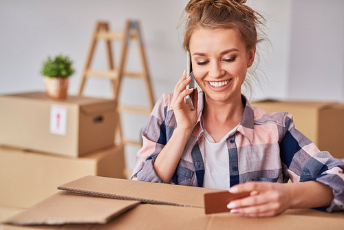 Smiling woman using phone while moving house