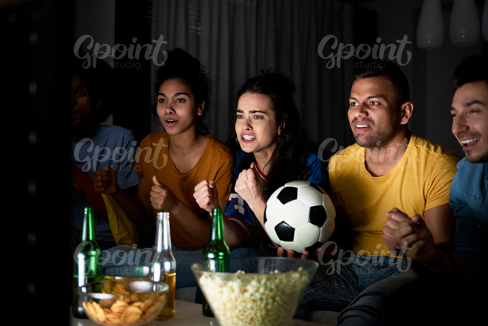 Group of friends cheering in front TV in the evening