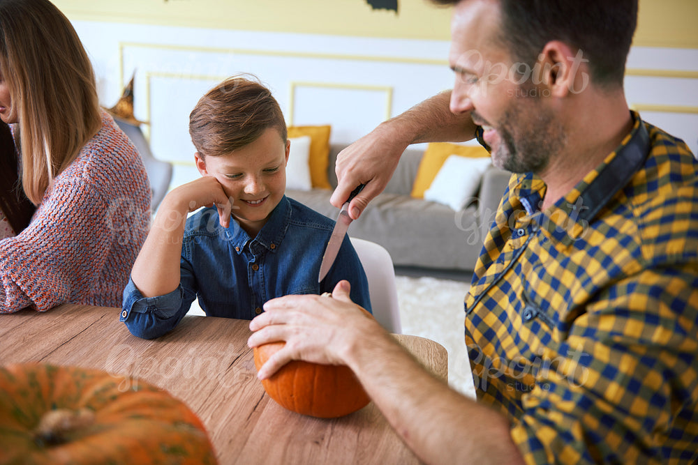 Father helping son in carving pumpkins