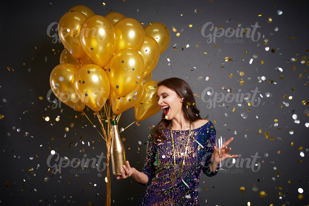 Woman with balloons and champagne among confetti
