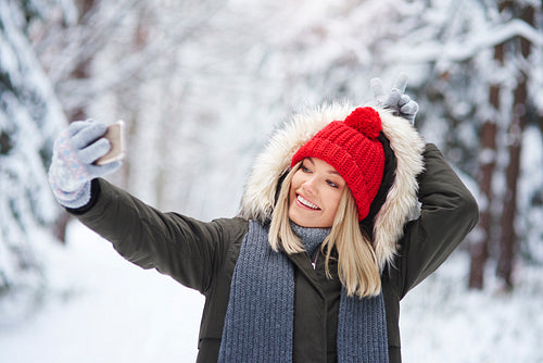 Playful woman making a selfie in winter forest