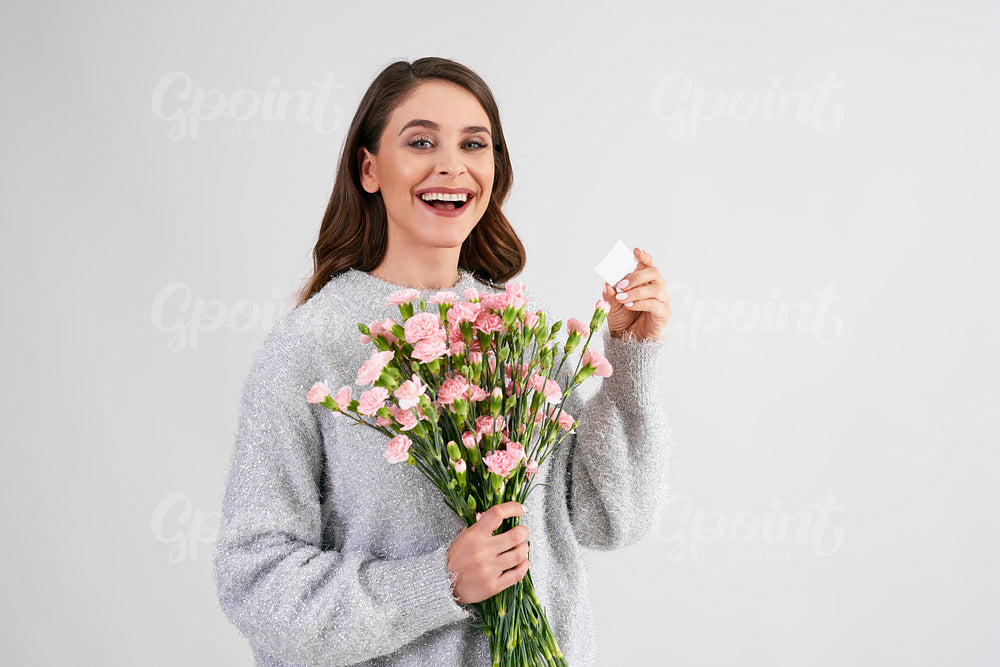 Smiling, beautiful woman holding bunch of flowers and greeting card