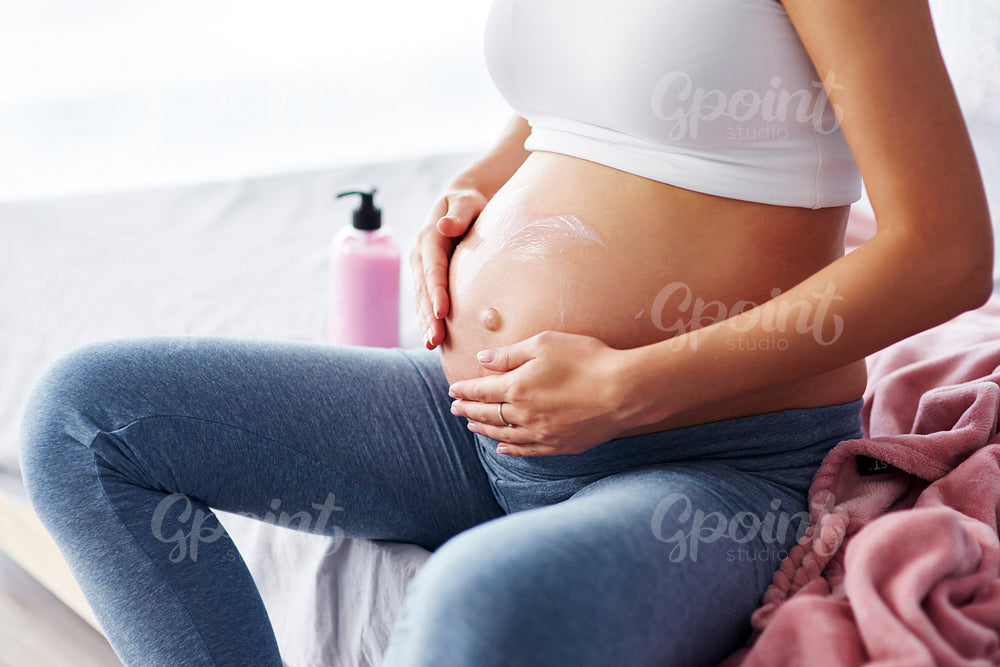 Close up of pregnant women applying moisturizer