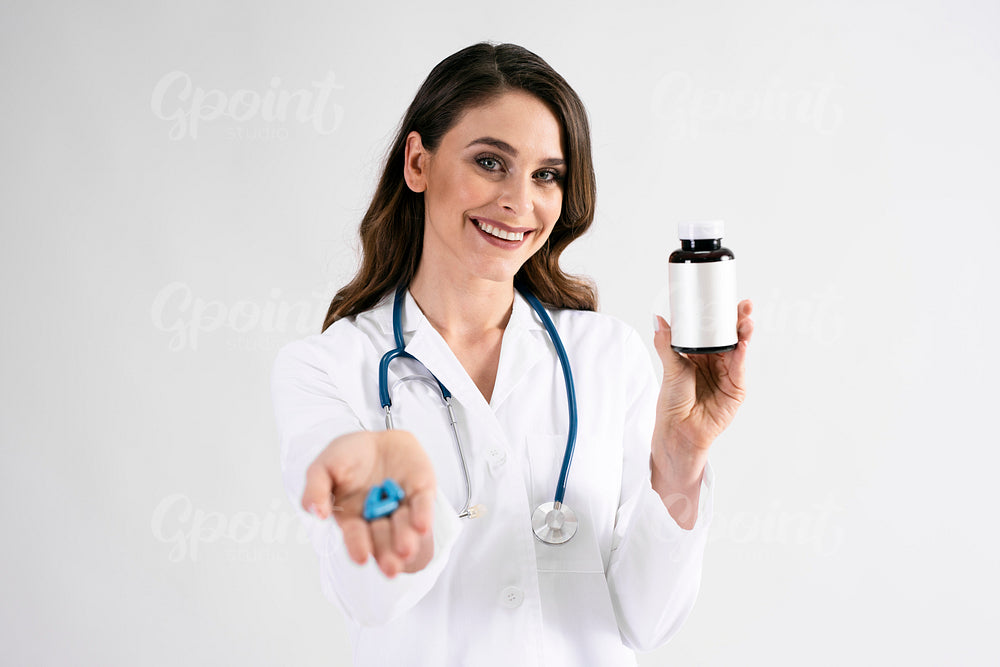 Smiling female doctor holding bottle of pills
