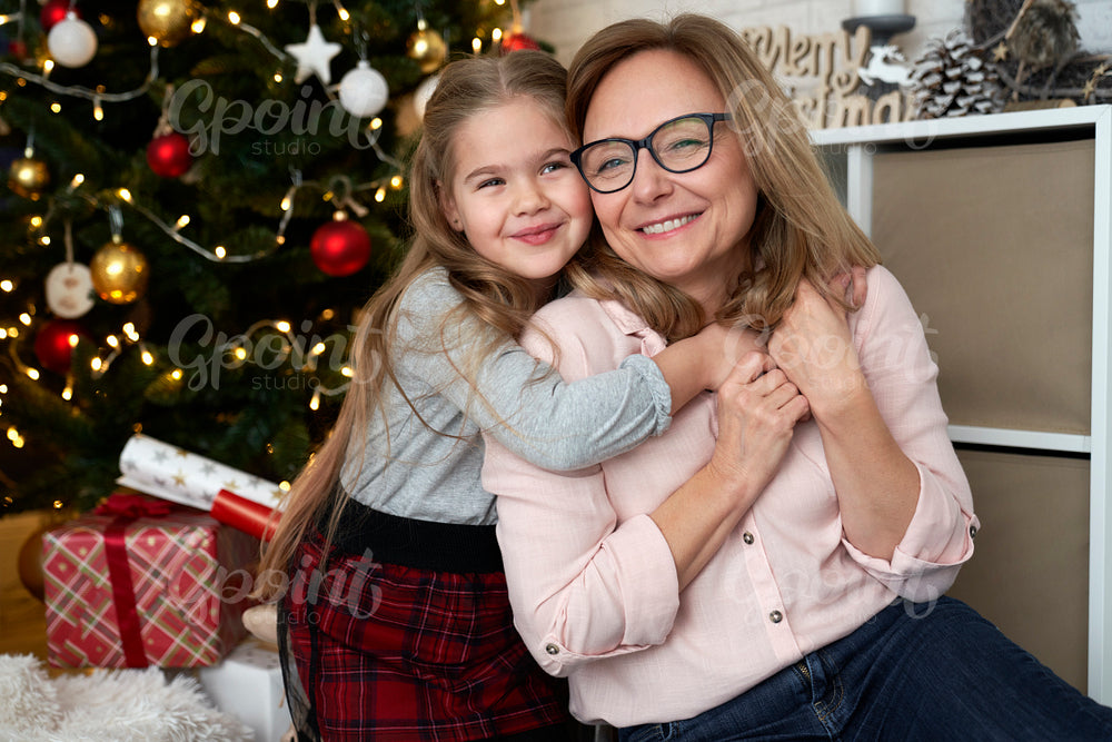 Portrait of grandmother and granddaughter embracing during Christmas