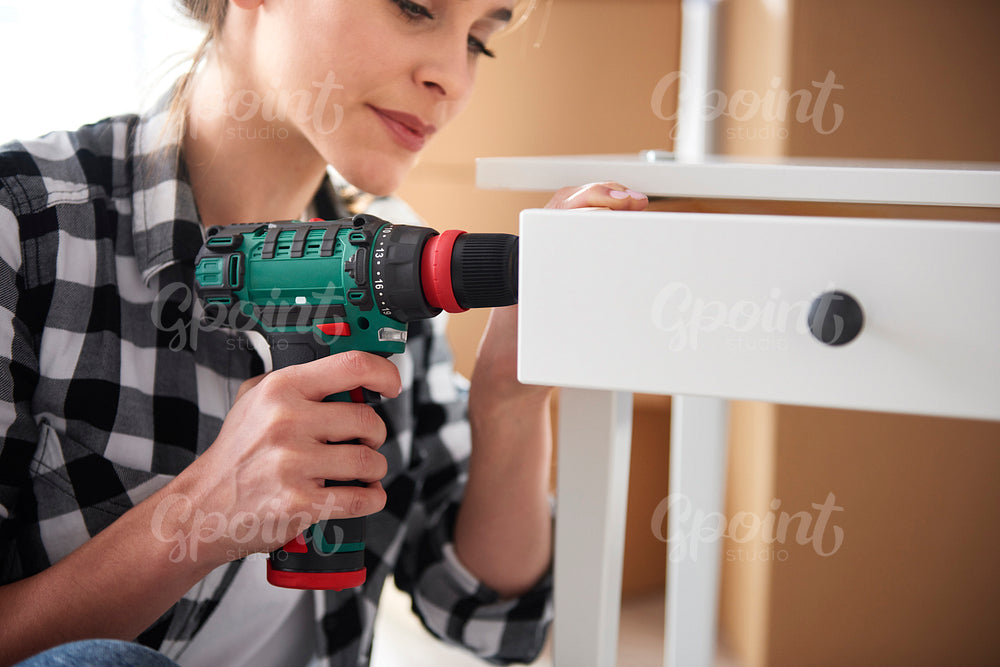 Independent woman repairing furnitures with electronic drill