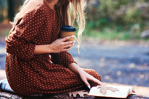 Woman sitting with a cup of coffee and books outdoors