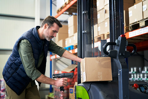Adult caucasian man working pulling forklift in a warehouse
