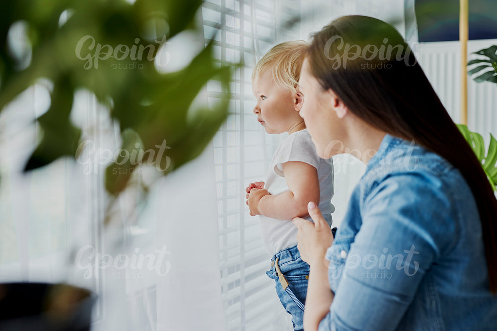 Mother and baby standing next to the window