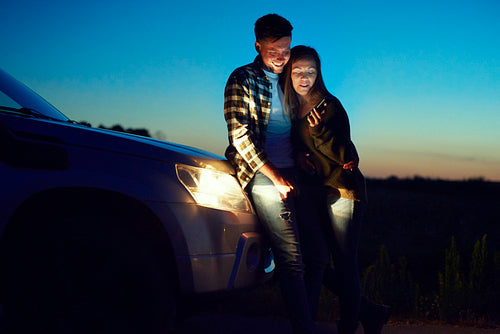 Loving couple using mobile phone during road trip at night