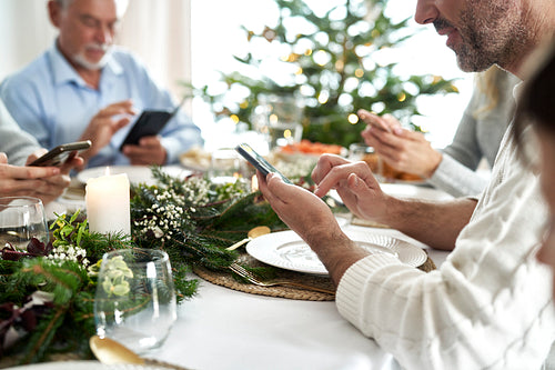 Family of caucasian unrecognizable  people sitting in silence and using phones during Christmas Eve