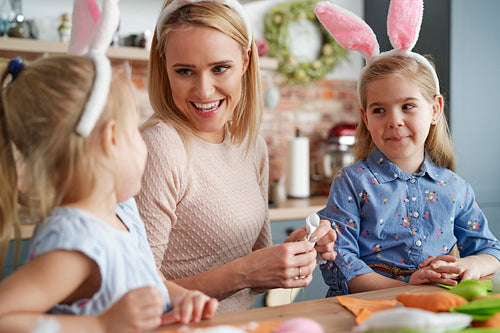 Mother and two daughters spending time together creating Easter decorations