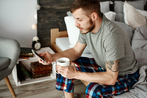 Man with coffee and mobile phone texting
