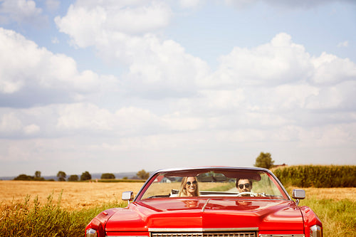 Front view of smiling couple in a red car