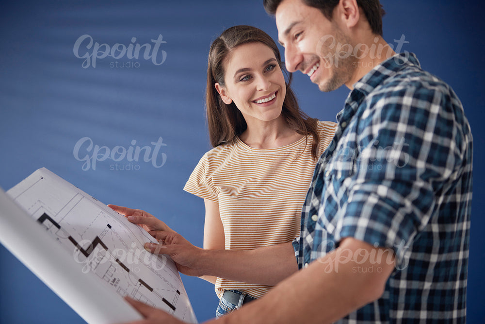 Couple browsing blueprint of newly bought house