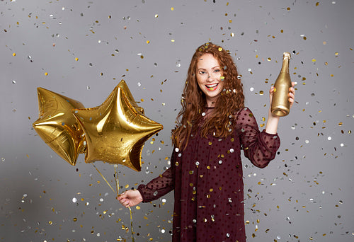 Happy woman with champagne and star shaped balloons