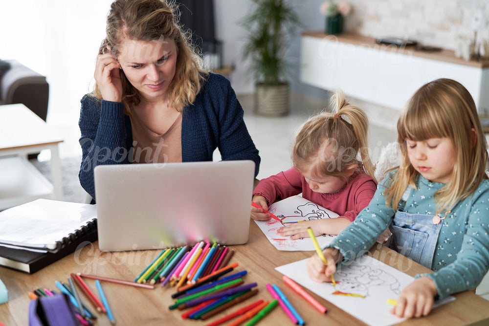 Mother working at home and looks after her daughters