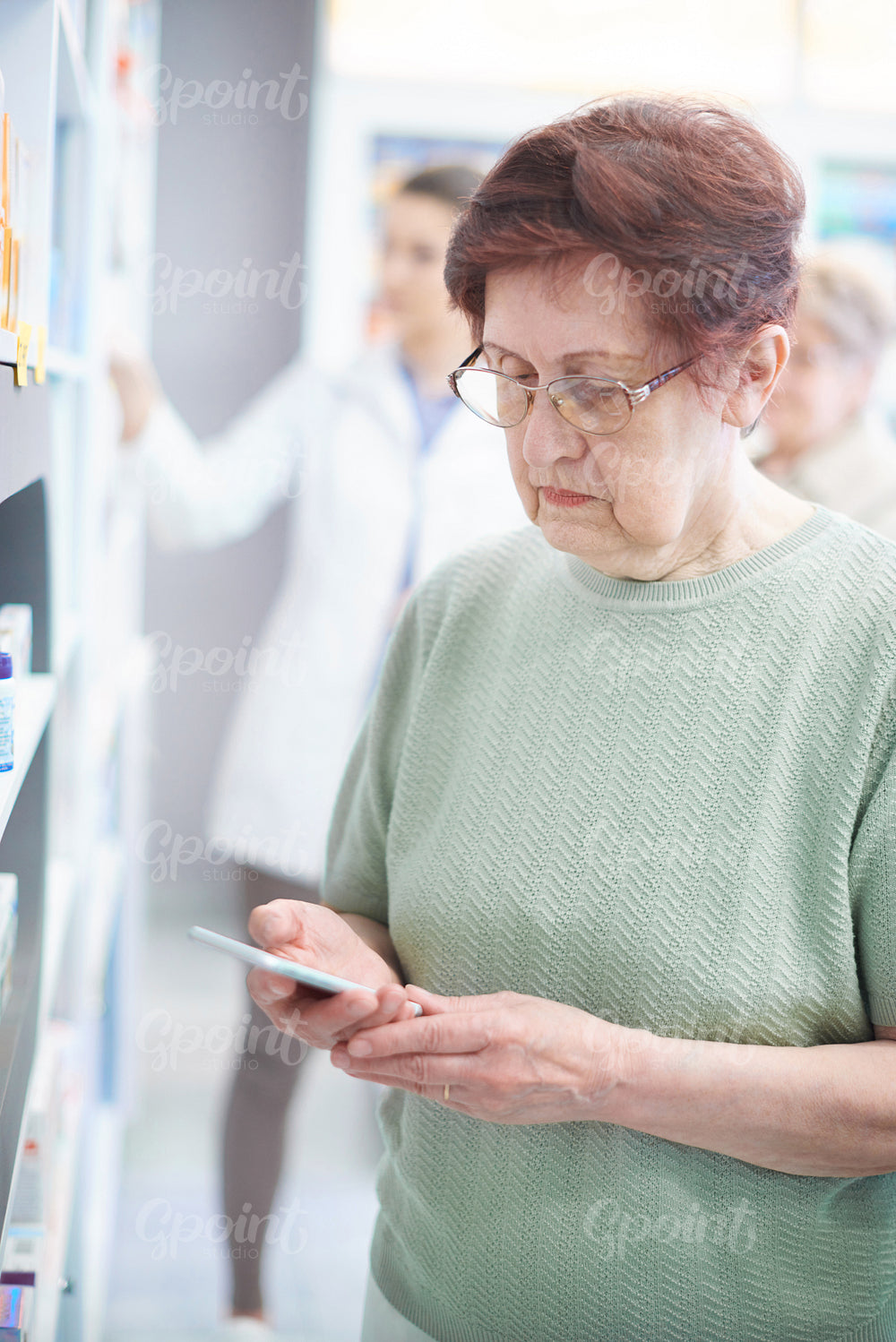 Mature woman using smartphone in drug store