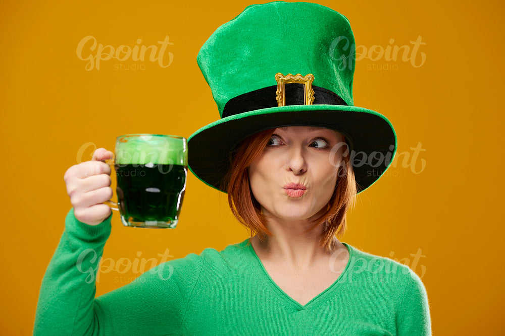 Playful woman with leprechaun's hat looking at beer