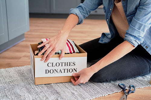 Woman  preparing box for clothes donation