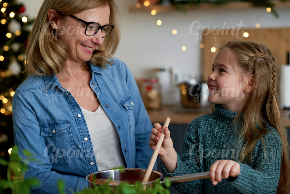 Happy grandma and little granddaughter cooking together in the kitchen