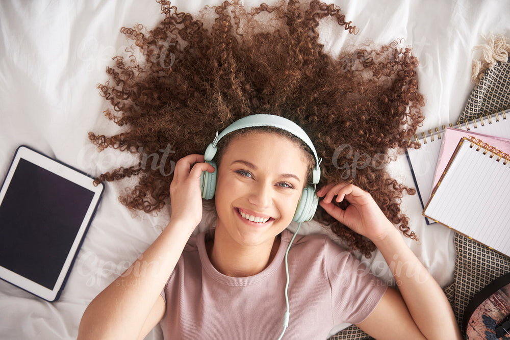 Beautiful teenage girl listening to music in her bed