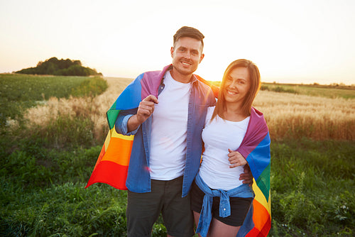 Portrait of smiling young couple with  rainbow flag