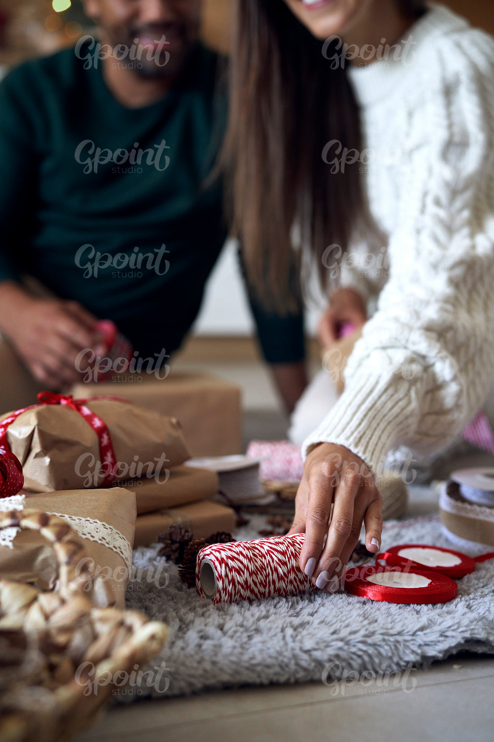 Couple choosing ribbon for Christmas present at home 