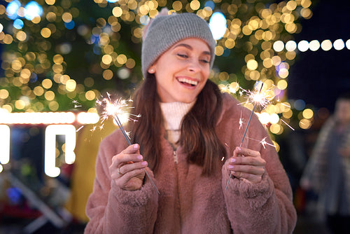 Woman outdoors holding sparklers at night