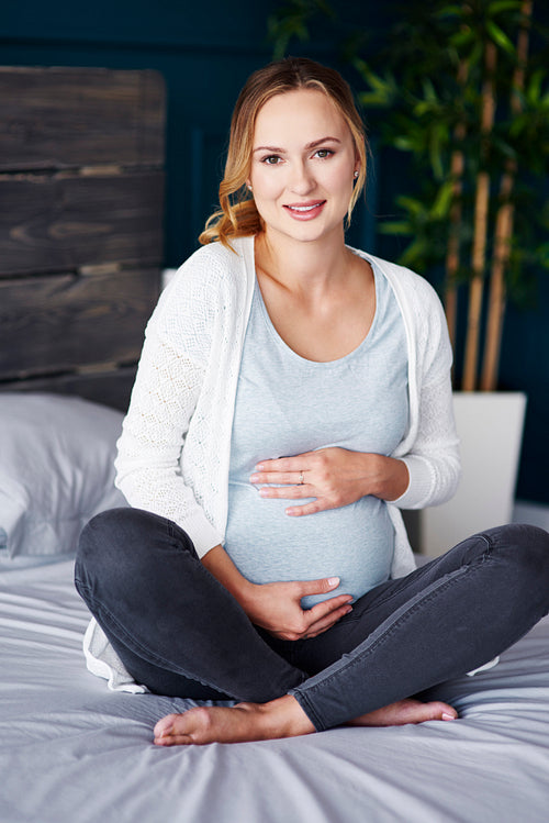 Portrait of cheerful pregnant woman at bedroom