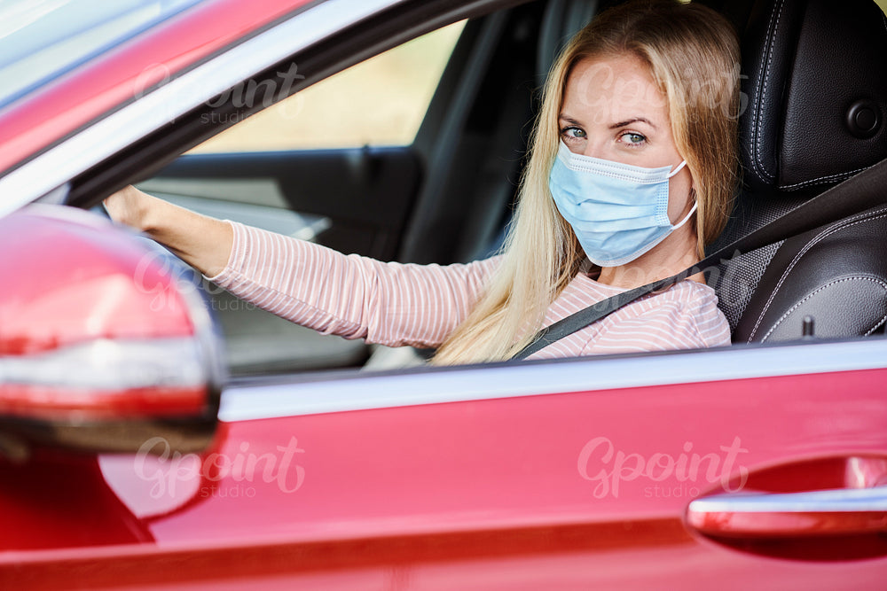 Woman in a protective mask driving a car