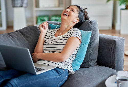 Young Asian woman laughing during a video conversation at home.