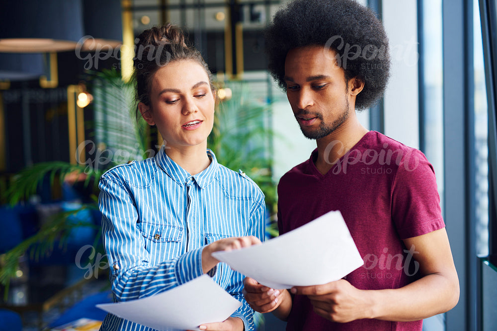 Heterosexual couple analyzing important documents in the office