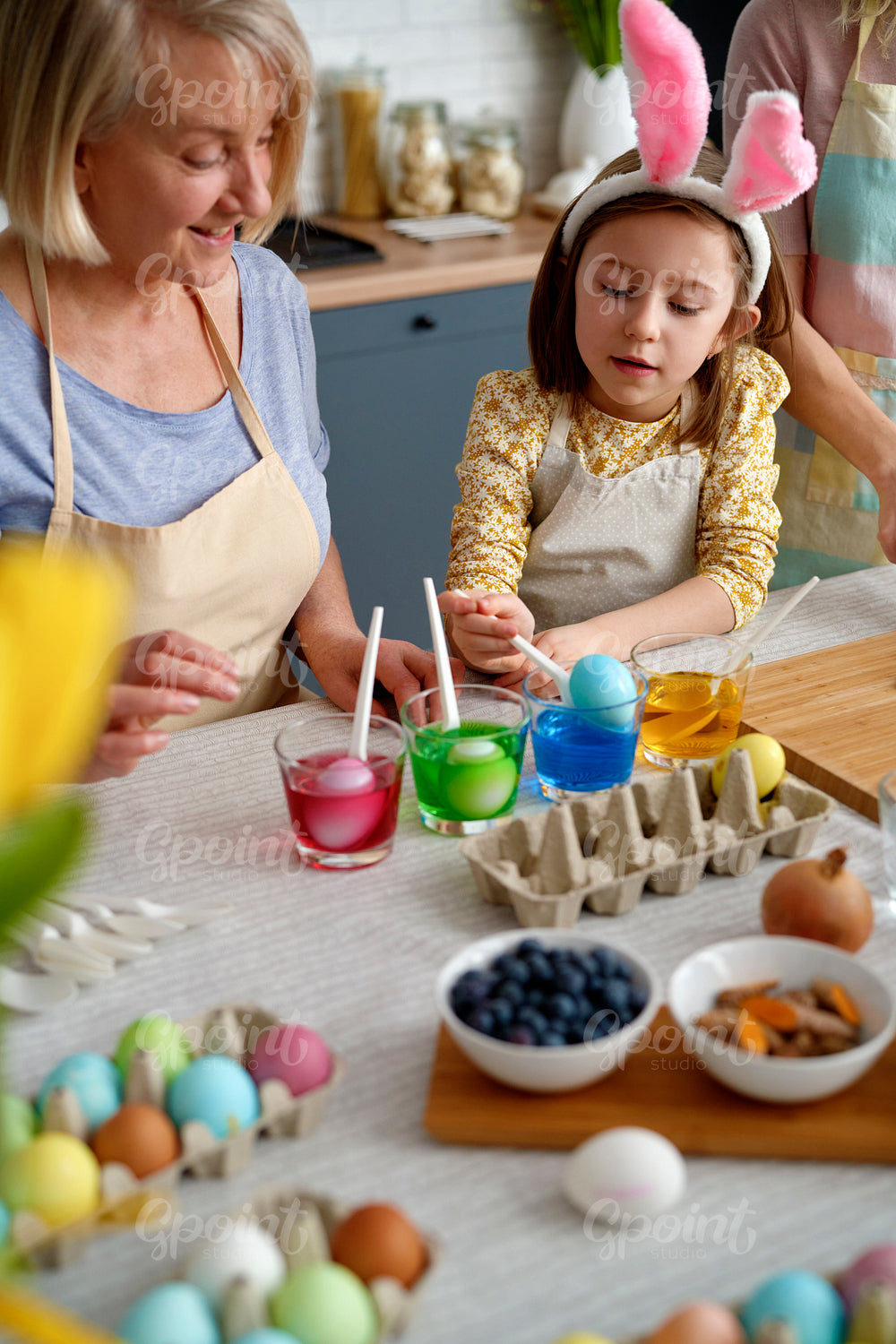 Little girl coloring Easter eggs with grandmother