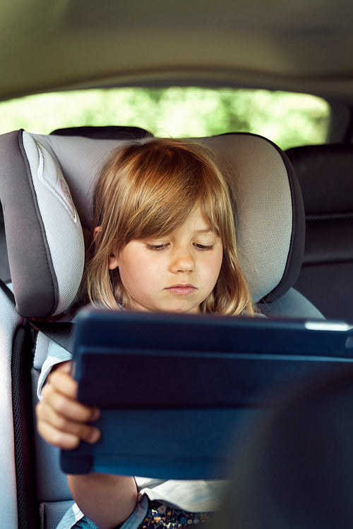 Close up of girl using digital tablet while sitting in car