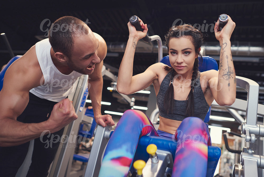 Personal trainer guding young woman at gym